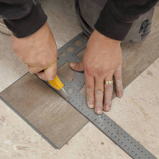 Man cutting lvp flooring for installation